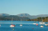 Pleasure yachts moored on the calm water of Lake Windermere in the Lake District in Cumbria against a mountain backdrop