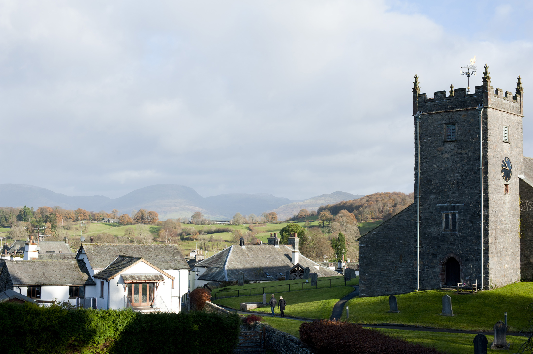 an image of Old stone church and cottages in Hawkshead in Cumbria, one of the most popular tourist villages in the English Lake District