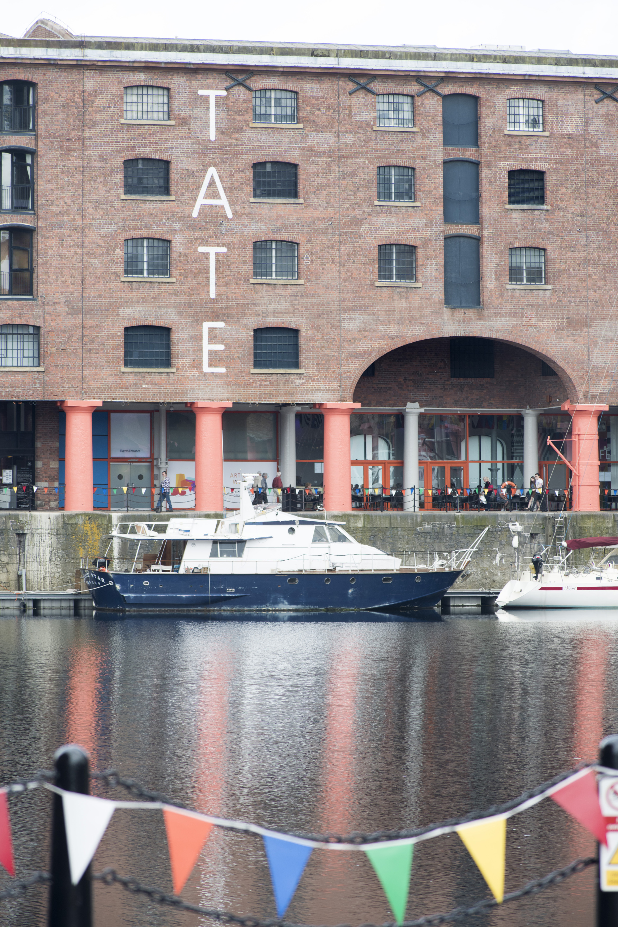 an image of Row of little flags in foreground on view of boat docked at the Liverpool Albert Dock in the United Kingdom