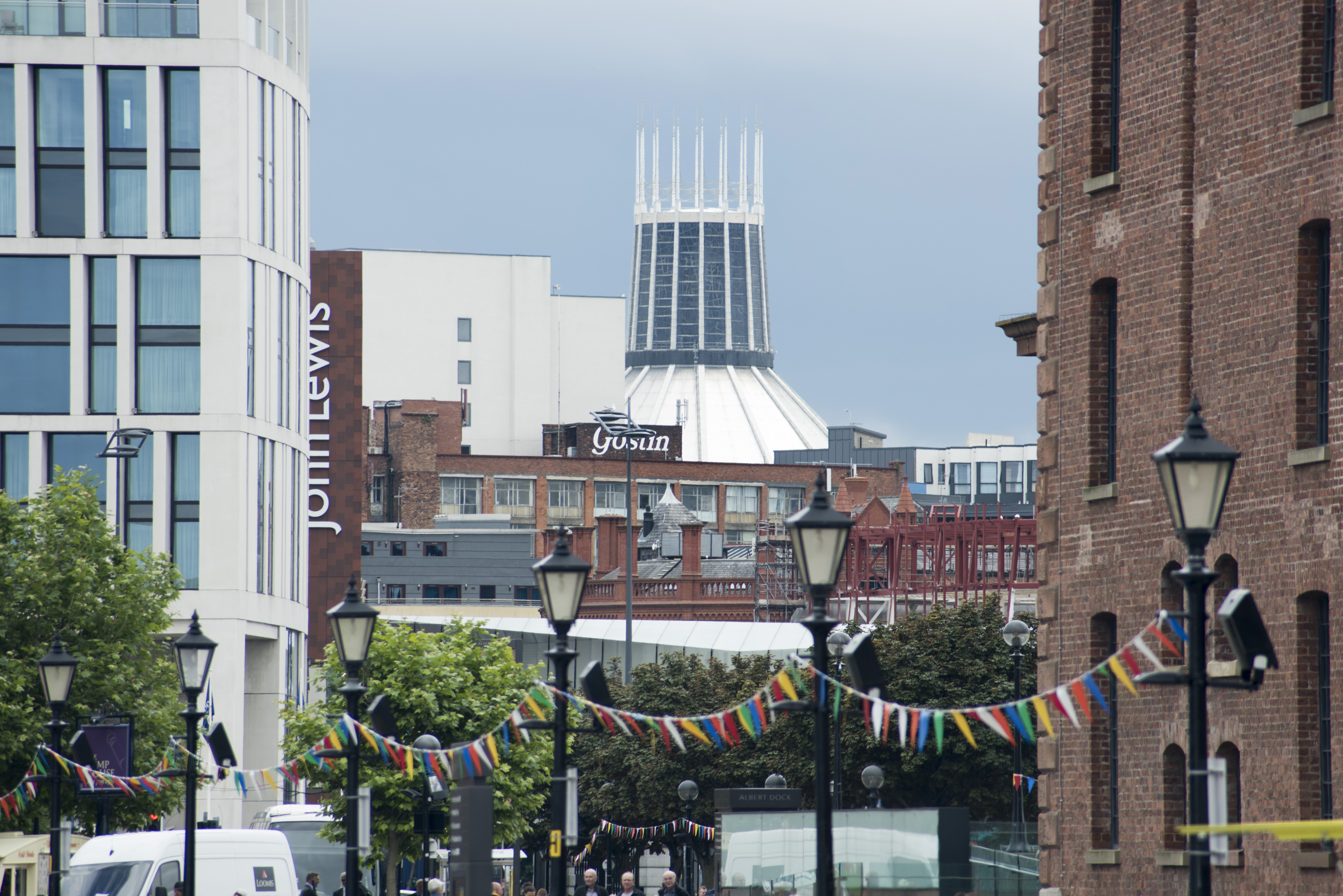 an image of Row of six streetlamps connected with little flags under view of Liverpool Cathedral in the United Kingdom