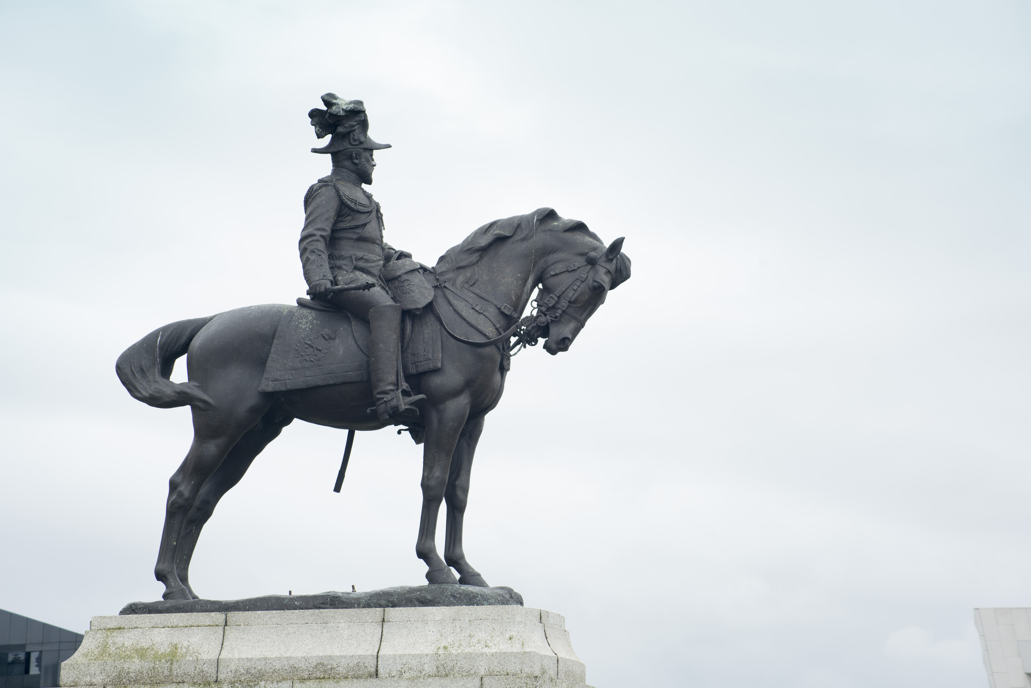 an image of Side view of Edward the Seventh sitting on horse statue with copy space in overcast gray sky
