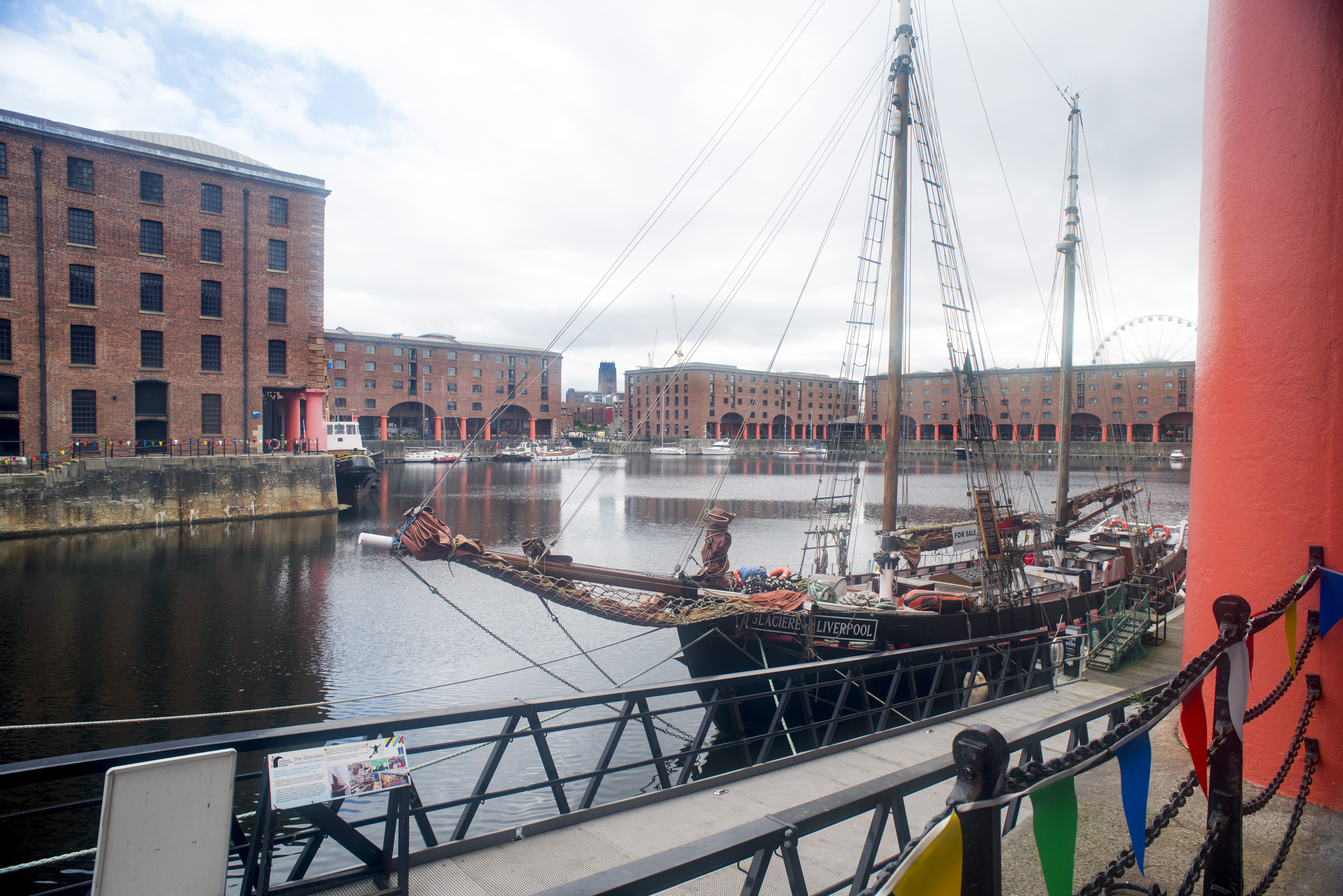 an image of View old fashioned schooner boat from railing beside red columns at the Liverpool Albert Dock in the United Kingdom