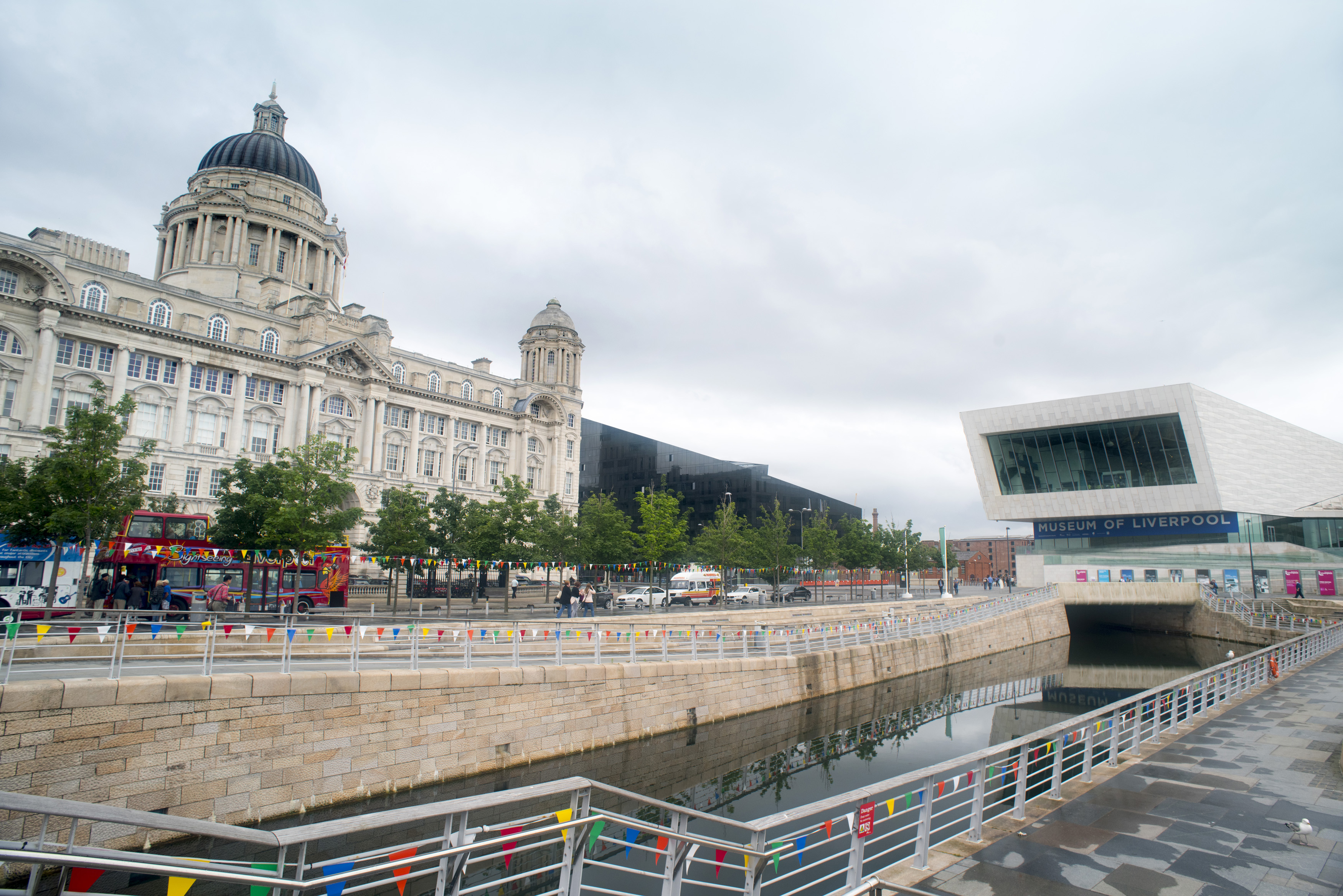 an image of Narrow canal with railing and steps leading to the Museum of Liverpool, with the Port of Liverpool Building in the background in the United Kingdom