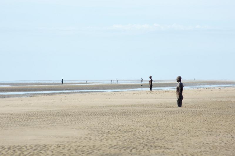 Another Place by Antony Gormley, Crosby Beach, Liverpool with 100 cast iron statues standing facing out towards the ocean