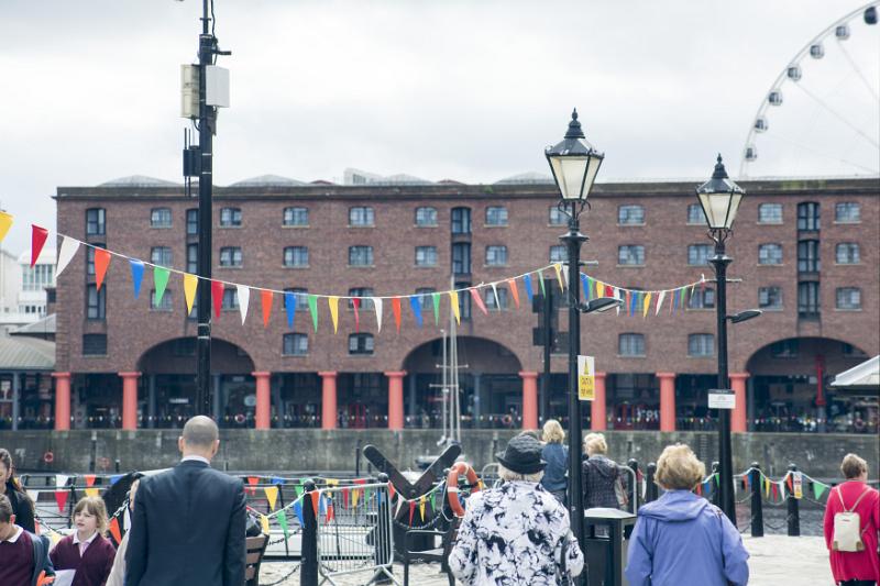 People in cool weather clothing gathering near Liverpool Albert Dock outside under old fashioned street lamps