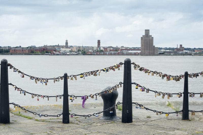 Various padlocks on railings near old mooring posts at Liverpool Mersey waterfront