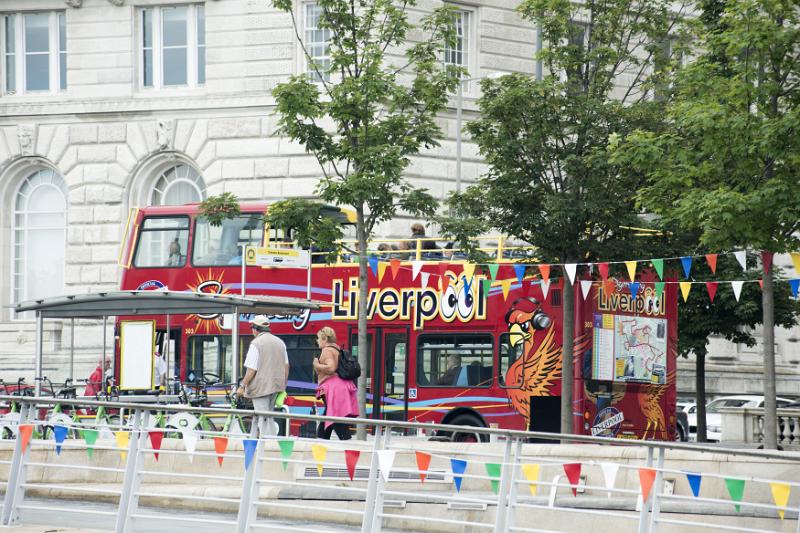 Traditional British red open top double decker tourist bus, Liverpool, England with colorful bunting and pedestrians