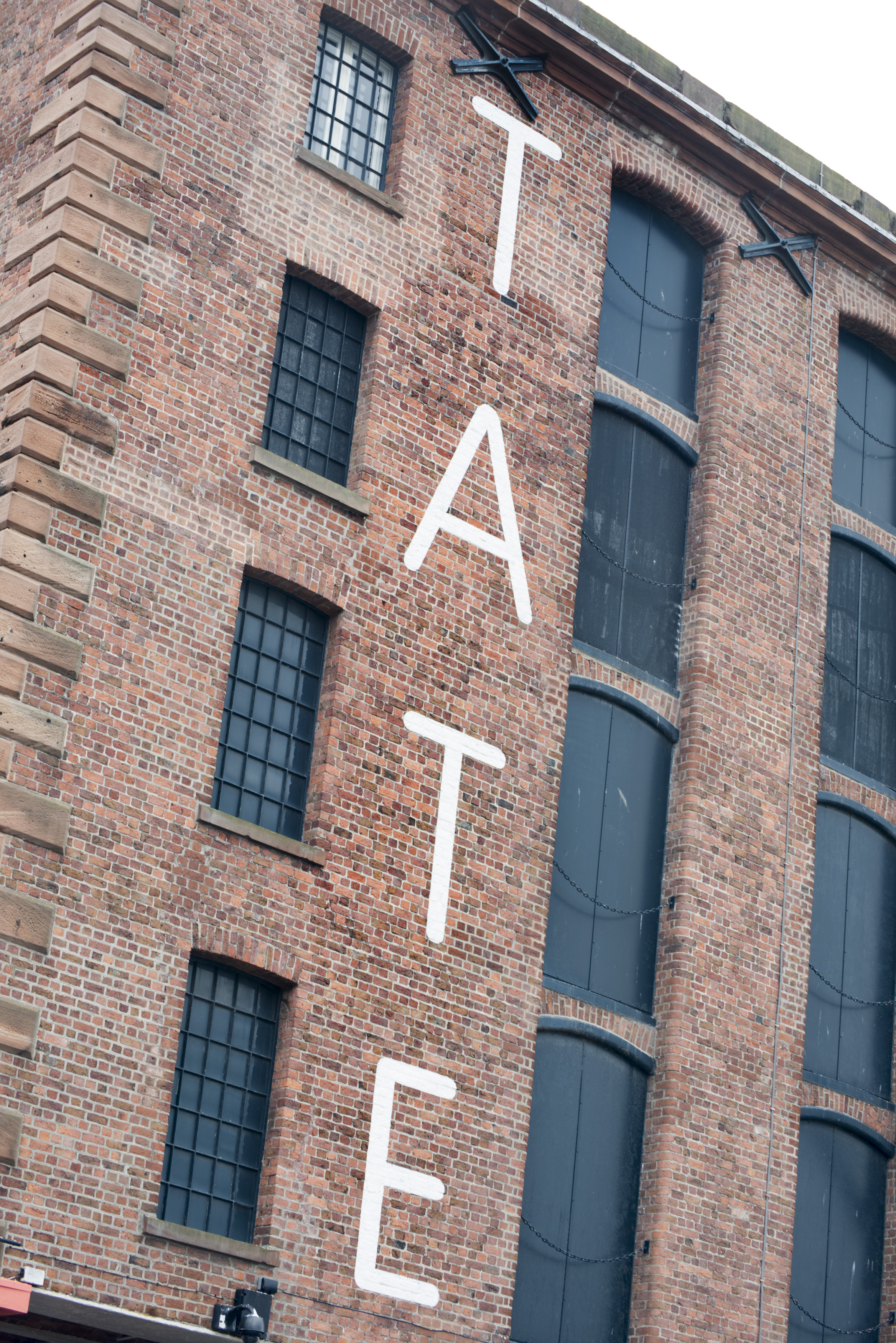 an image of TATE letters painted on brick of old building at the famous Liverpool Albert Dock in the United Kingdom