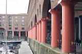 Massive red columns standing above boats docked with piers at Liverpool Albert Dock