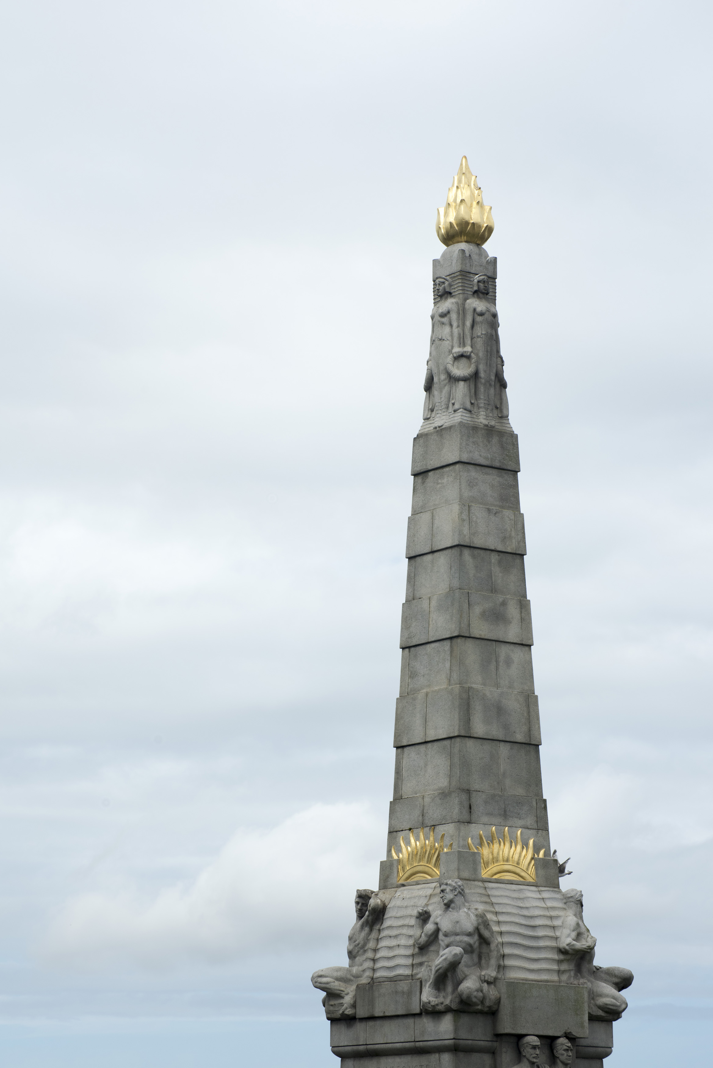 an image of Golden colored torch ornament on top of stone  pinnacle in Liverpool, memorial to those lost on the Titanic, United Kingdom