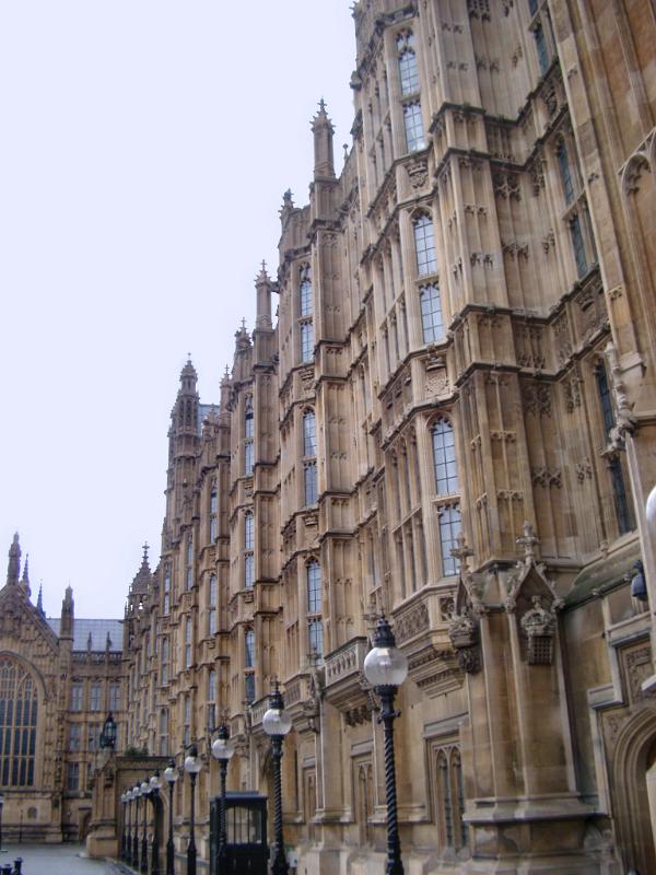 View down the length of the Gothic revival stone carved facade of the historical Palace of Westminster, London