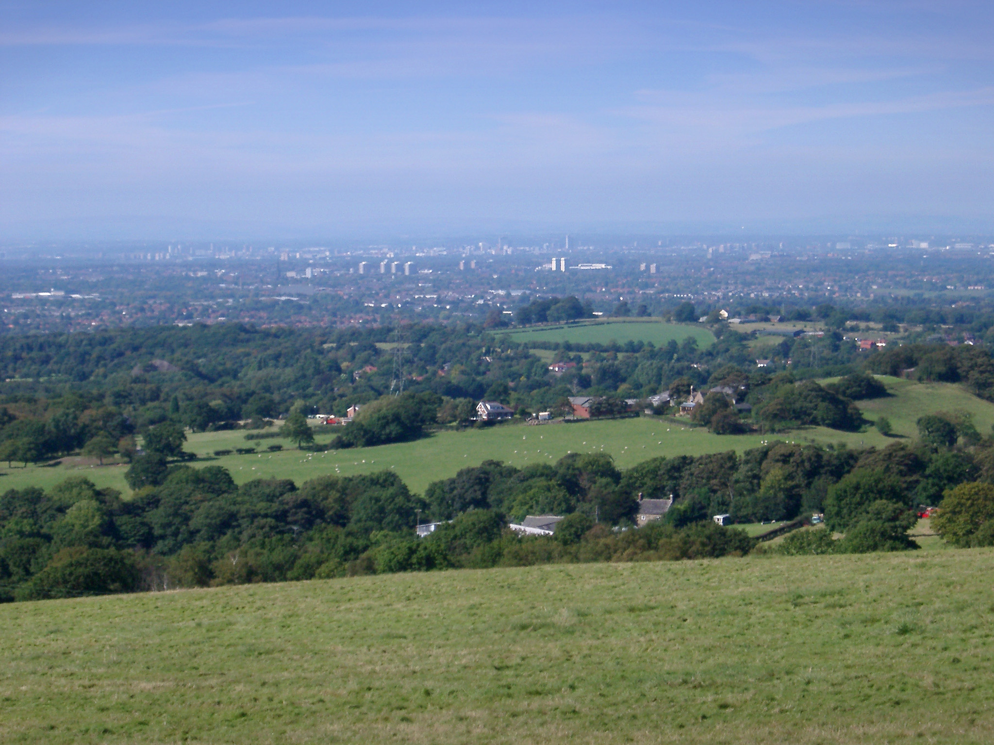 an image of Lush English countryside looking towards the city of Manchester in the distance with the view encompassing the whole city
