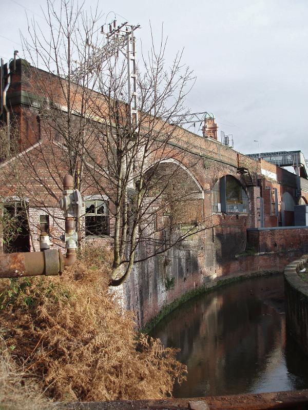 Central Manchester industrial canals bordered by the rundown arches of a railway and old warehouses