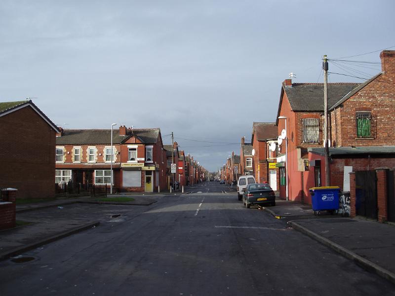 Side street in Moss, Manchester showing the typical red brick architecture, parked cars and a garbage bin