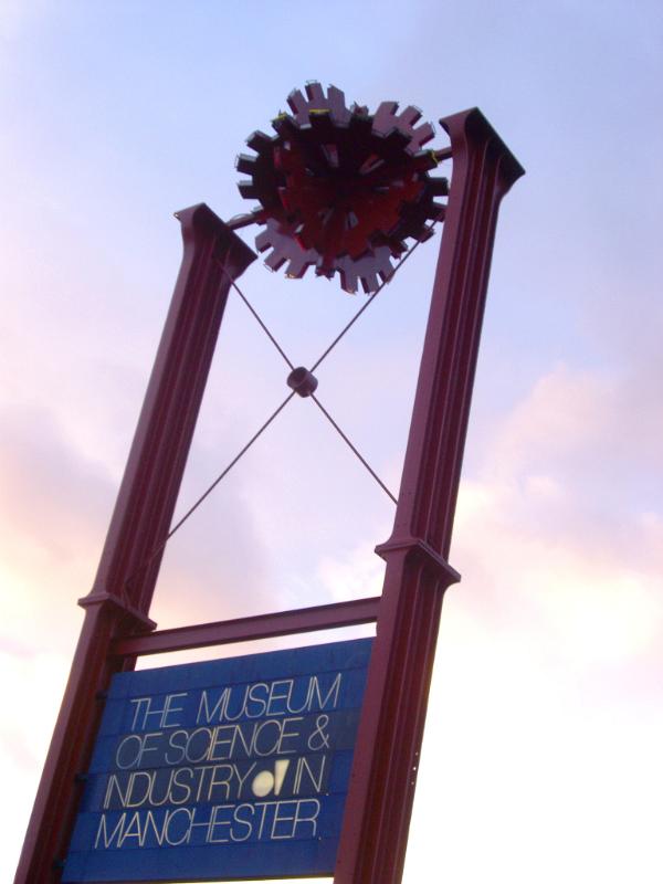 Museum signboard for the Museum Of Science and Industry in Manchester, UK, silhouetted against a delicate pink sunset sky