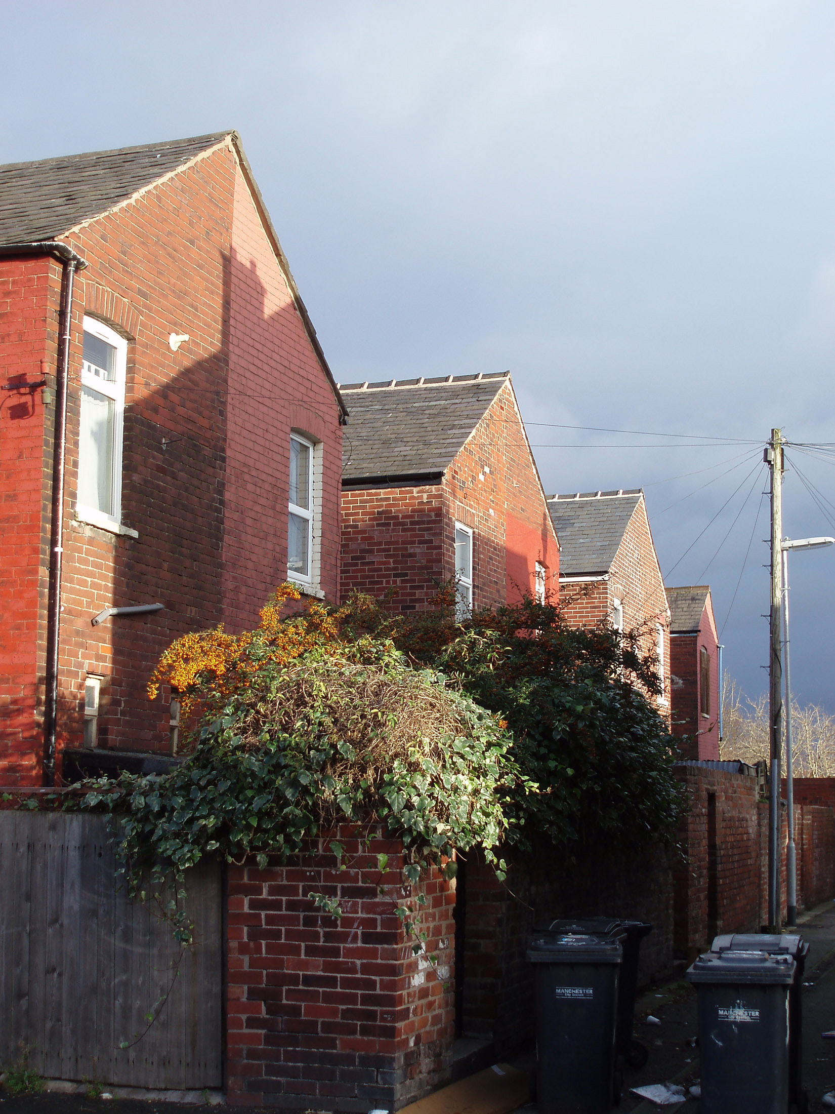 an image of Moss Side Manchester with rows of terraced red brick Mancurian houses in narrow urban streets