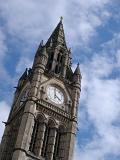 Ornate Gothic revival external facade of the Manchester Town Hall clock tower against a cloudy blue sky