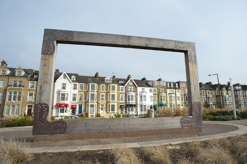 a large wooden picture frame at the west end gardens in morecambe, when viewed from the opposite side allows visitors to frame a bleak vista of morecambe sands