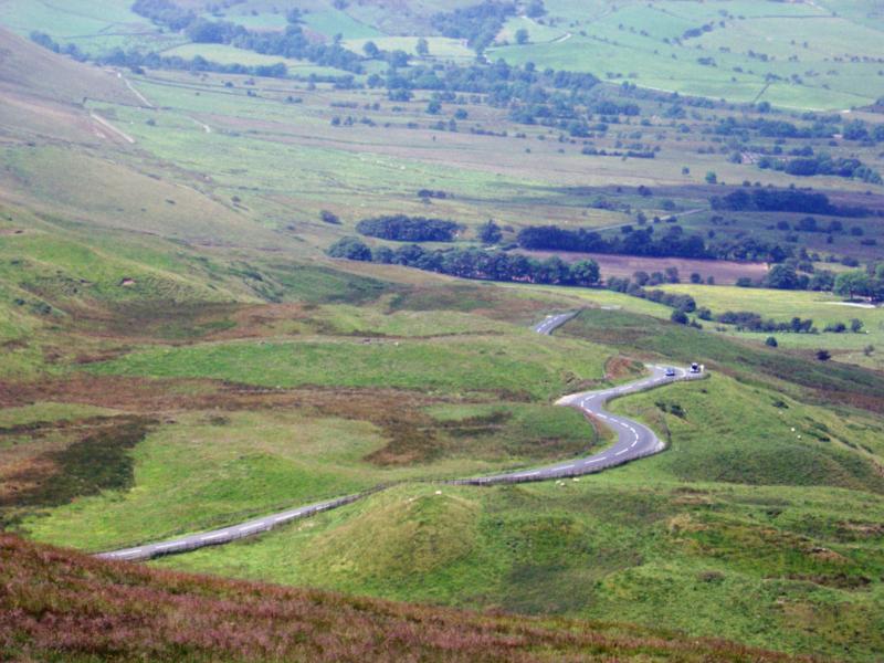 Winding road snaking through lush countryside near Edale in the Dales, Peak District, Derbyshire