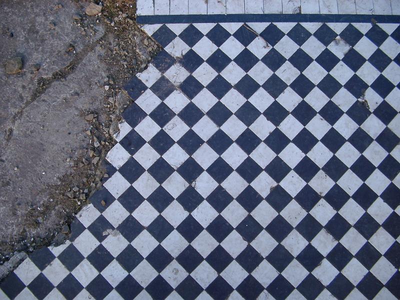 Damaged geometric tiled floor with an alternating grey and white diamond pattern at the Lever Park ruins