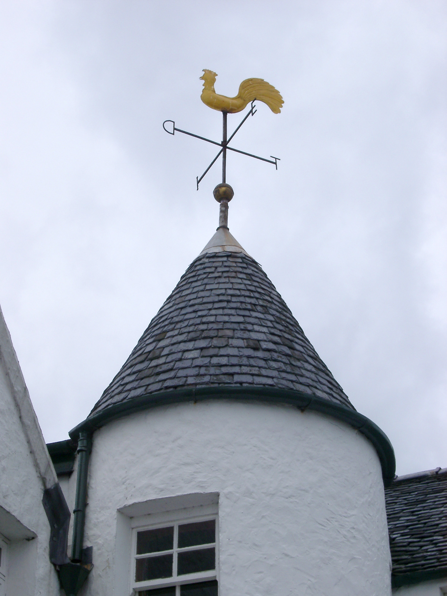 an image of Weather vane in the shape of a cock on top of a small cylindrical tower with a slate roof