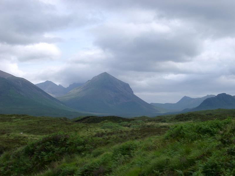 Lush green Scottish landscape with high rugged mountains and a verdant plateau in the foreground under a cloudy sky