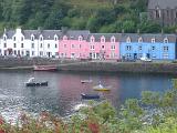 Colorful terraced houses and hotel on the waterfront overlooking fishing boats on the water in Portree, Isle of Skye