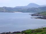 Scenic view of a loch in Scotland with inlets, bays and a golden beach backed by rugged mountains on a misty day