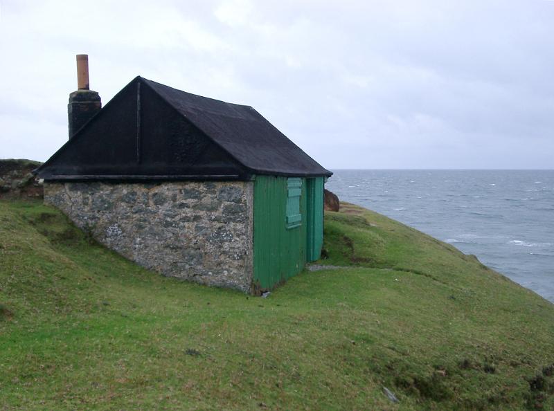 Stone shed or hut overlooking the ocean Stone shed or hut with a green facade on a headland overlooking the ocean providing shelter from the coastal weather