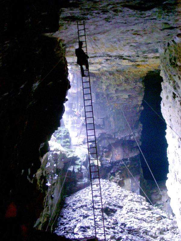 Interior of an old slate mine Interior of an old historic slate mine with the silhouette of a man on a ladder suspended from the ceiling and daylight entering from an opening on the side