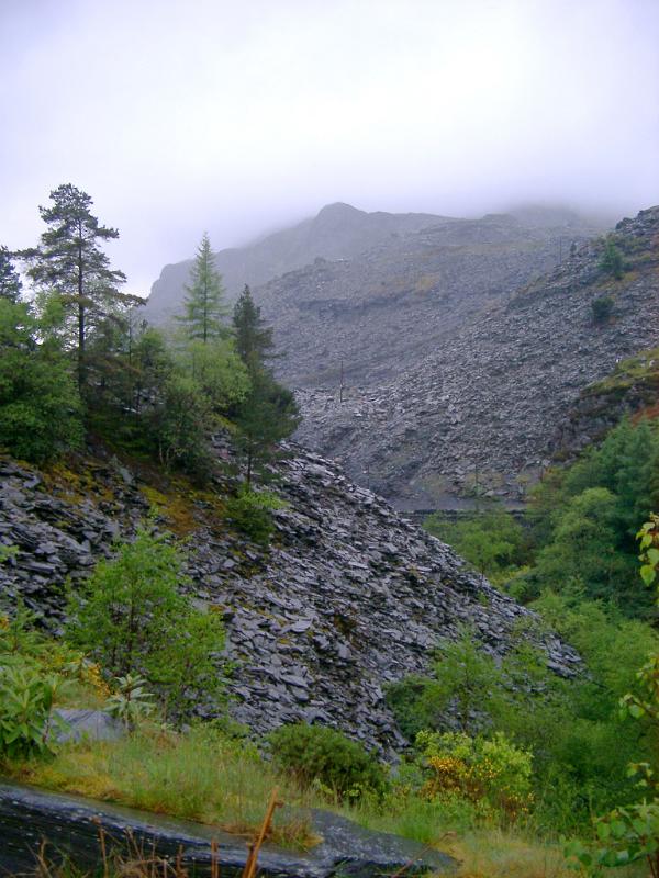 Slag heap from slate mining, Blaenau Ffestiniog Huge slag heap from slate mining, Blaenau Ffestiniog, slowly being reclaimed by trees and vegetation on a misty rainy day