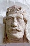 The sculpted stone head of an ancient imposing king wearing a crown, symbol of royal historical authority, close-up