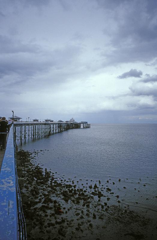 View along the side from the land of the historic Victorian pier on Llandudlo North Shore, Wales on a cold overcast day