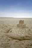 Sandcastle decorated with shells on a beach at the seaside with golden beach sand a reminder of as happy afternoon spent playing in the sand