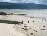 Wooden groynes in the sand on the beach at Barmouth, Wales built to control coastal erosion from the tides