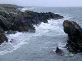 Stormy sea with breaking waves lashing a rocky coastline on a grey misty day