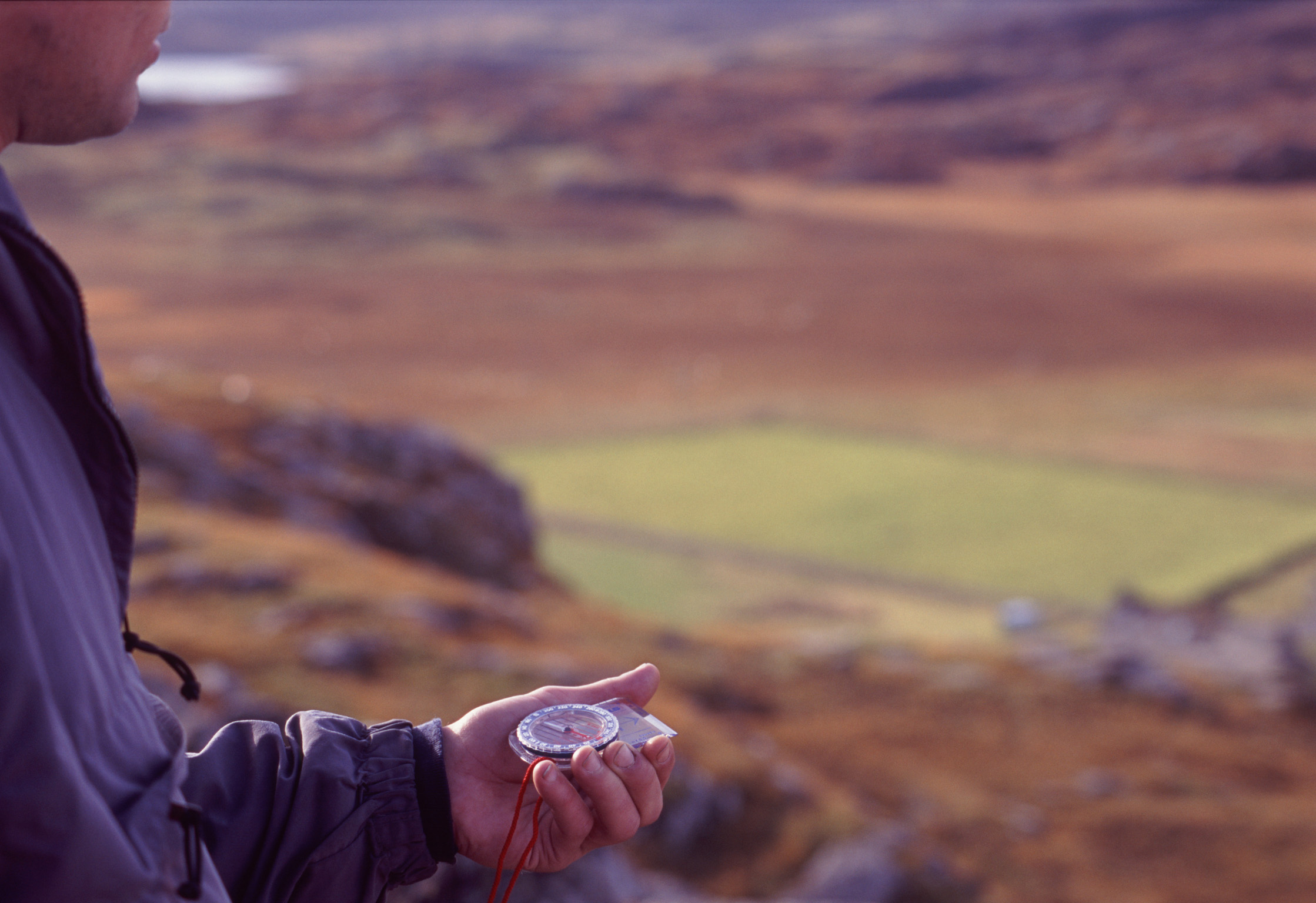 an image of Man holding a compass in his hand when out walking in the mountains of Scotland to navigate using magnetic north