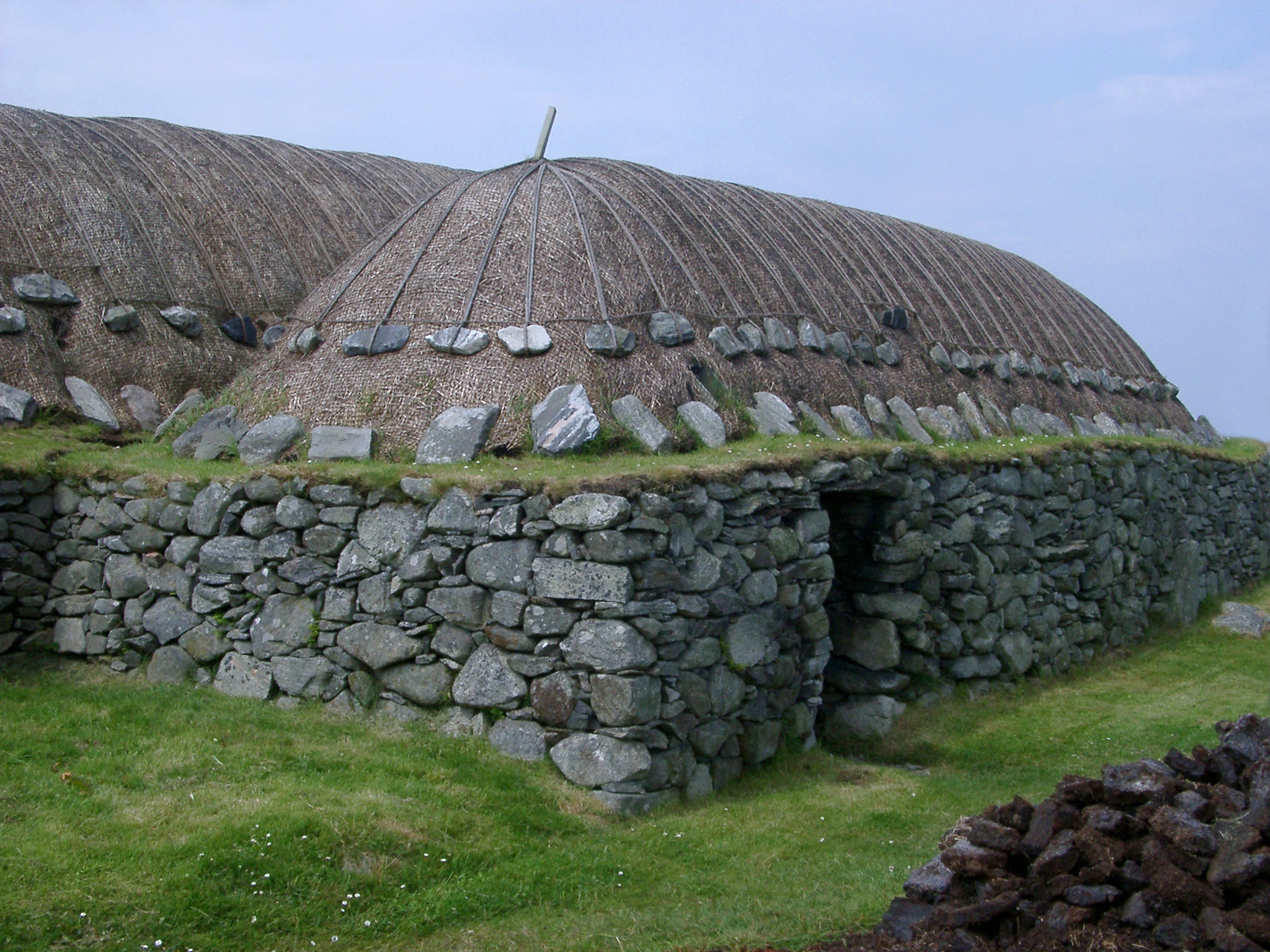 an image of Traditional blackhouse on the Hebrides with its thatched roof and double drystone walls inside which an open fire was built with no chimney so the smoke had to seep through the thatch
