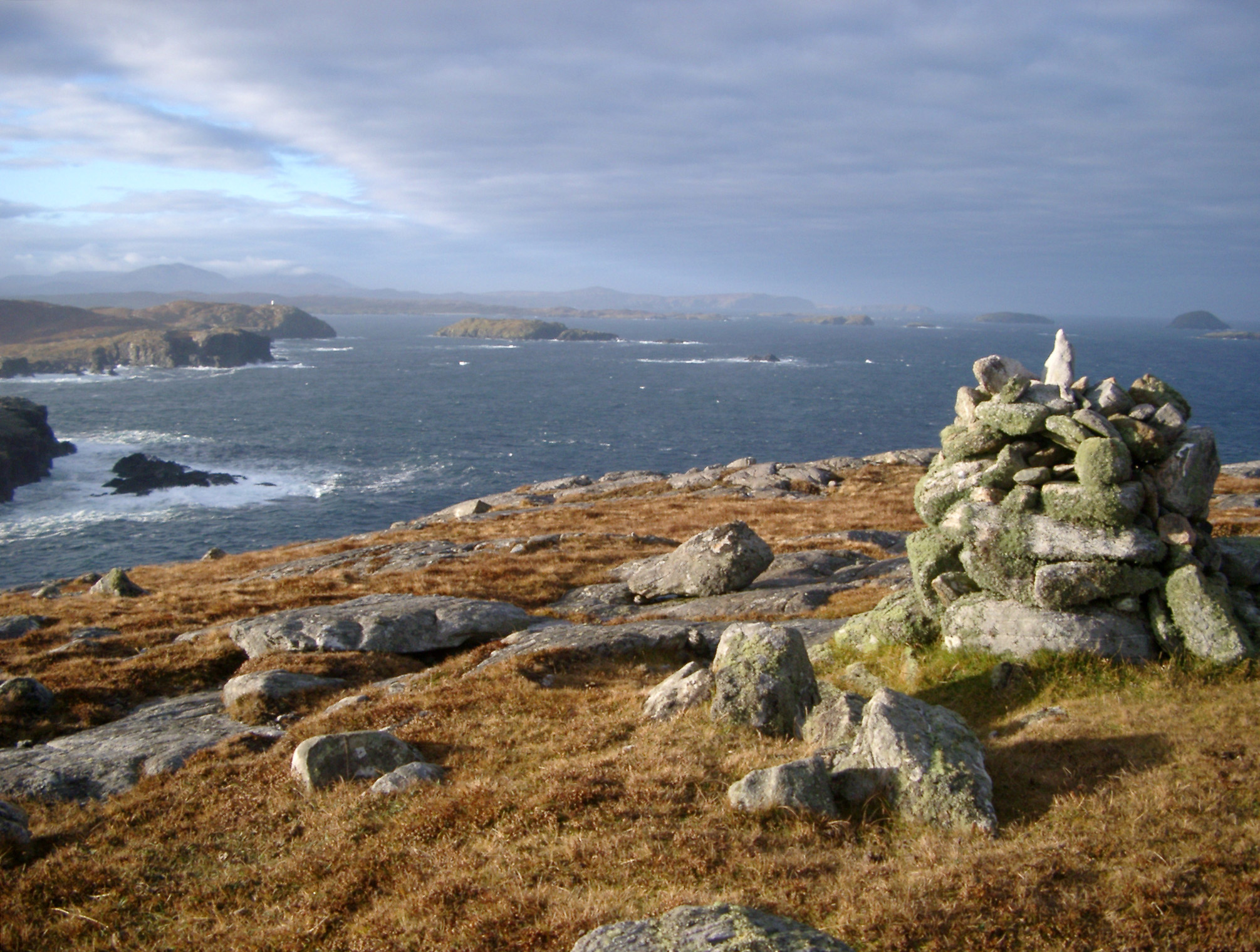 an image of Stone cairn on a coastal headland lookout overlooking the coastline of the Hebrides, Scotland on a stormy day