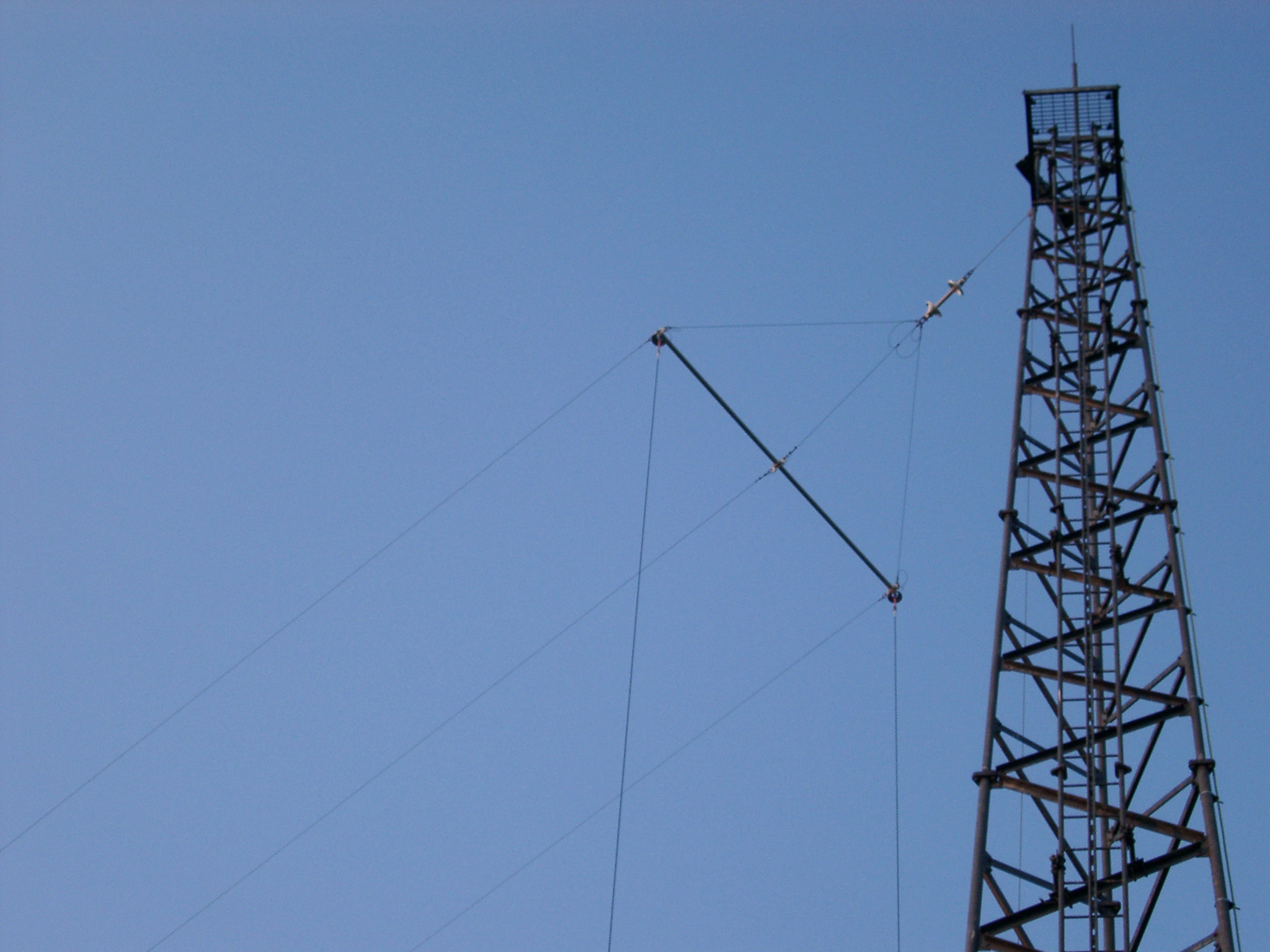 an image of The steel lattice framework of a tall radio mast with cable for short wave transmissions against a clear blue sky with copyspace