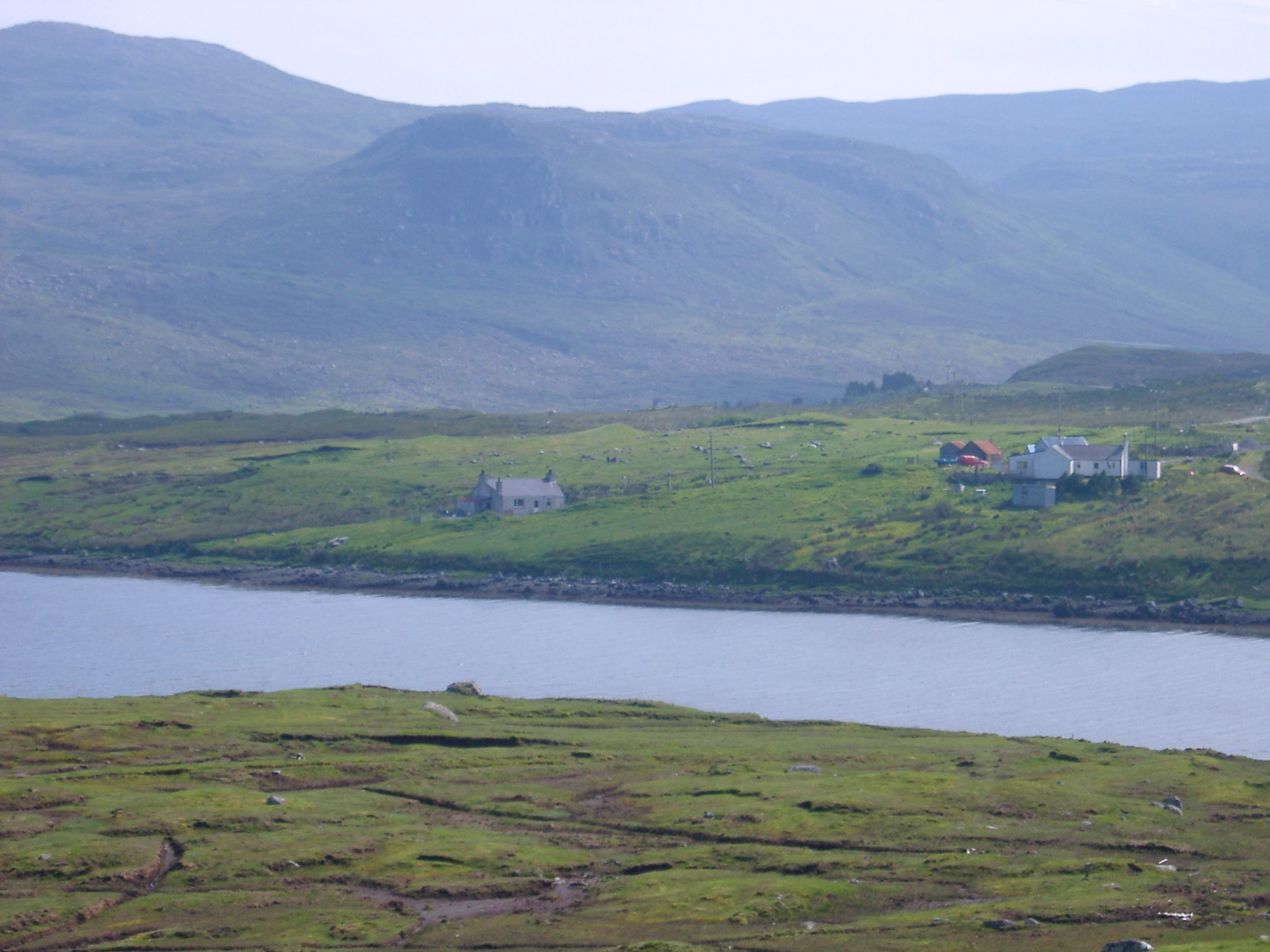 an image of Remote Valley Houses and Green Farmland on Scottish River Shoreline with Hills in Background