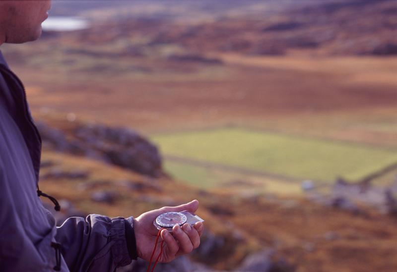 Man holding a compass in his hand Man holding a compass in his hand when out walking in the mountains of Scotland to navigate using magnetic north