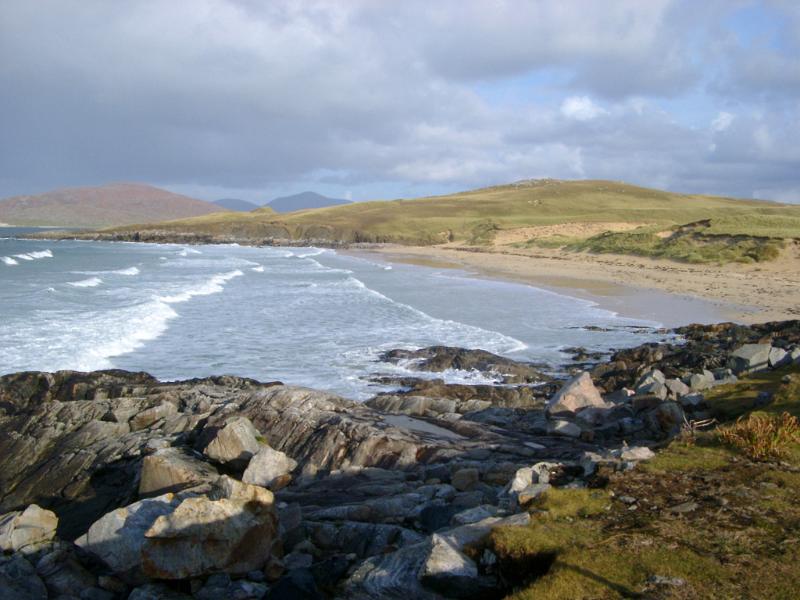 Sunny golden beach on the Isle of Harris, Hebrides with rolling breakers coming ashore on golden sand and rocks in the foreground