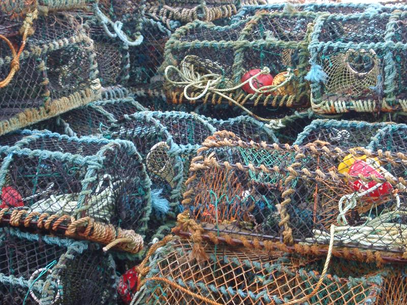 Background of old cylindrical wire mesh crab or lobster pots piled ashore waiting to be lowered into the sea for fishing
