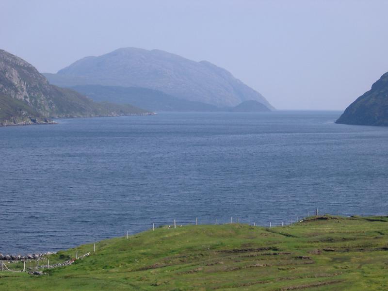 Coastal scene in the Inner Hebrides with a tranquil sheltered loch surrounded by mountain peaks, Scotland