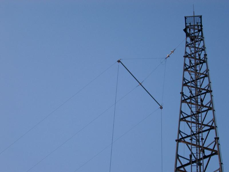 The steel lattice framework of a tall radio mast with cable for short wave transmissions against a clear blue sky with copyspace