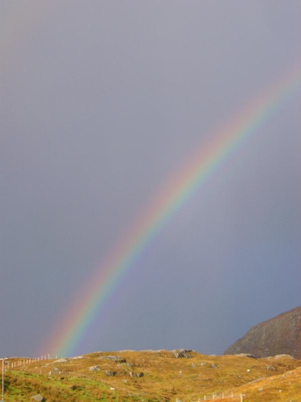 Colorful rainbow after a storm arcing through the misty sky to touch down on a mountain top