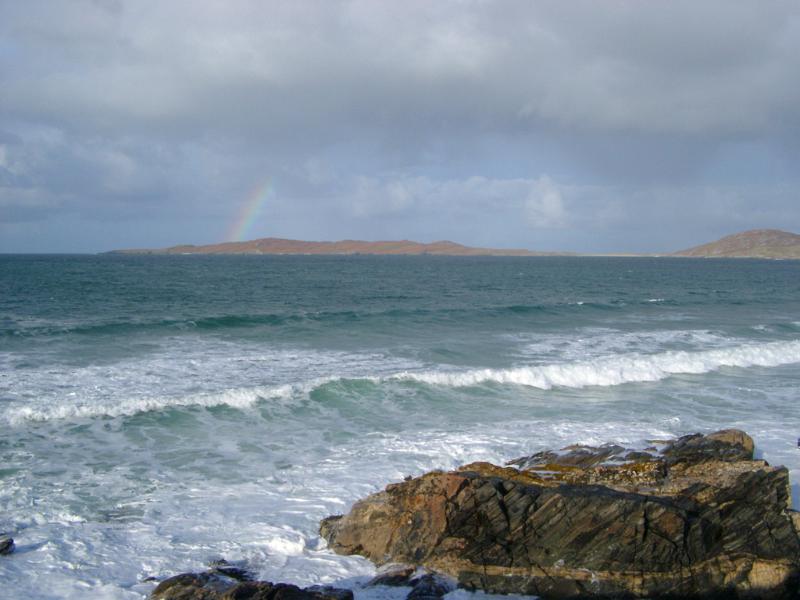Stormy seascape with breaking white waves and a distant rainbow off the Isle of Harris