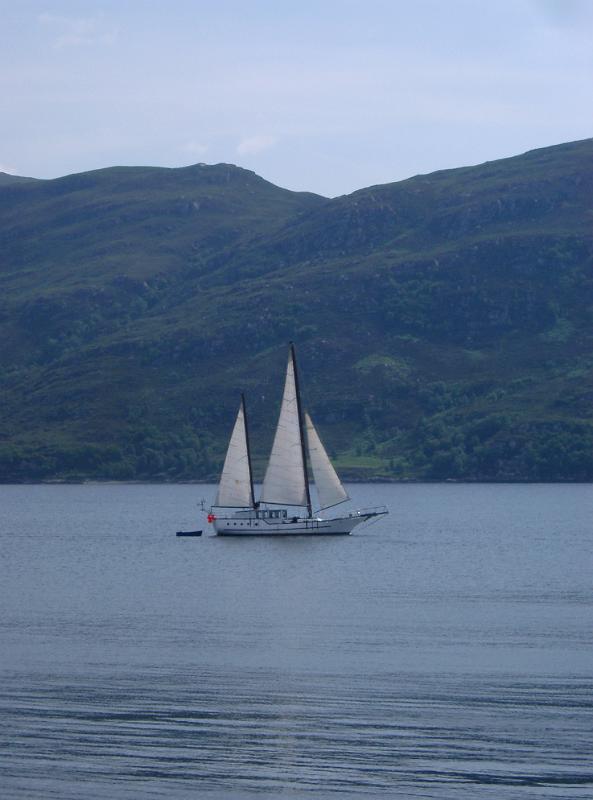 Sailboat Yacht Sailing on Scottish Loch on Overcast Day with Rolling Hills in Background