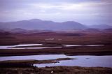 Hebrides landscape vista with purple colored mountains towering above a low lying coastal bog on a cloudy day, Scotland , UK